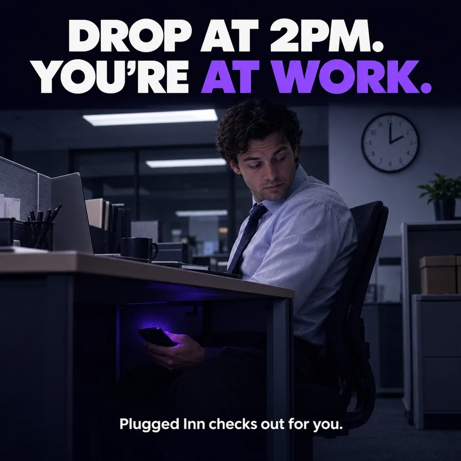An office worker checking a phone under the desk. Text: Drop at 2PM. You're at work. Plugged Inn checks out for you.